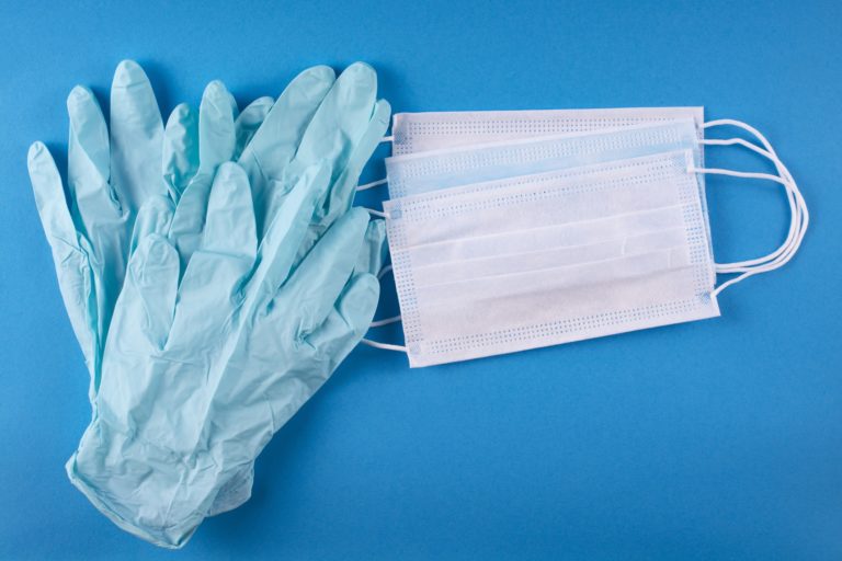 A pair of medical gloves and three masks on a blue background