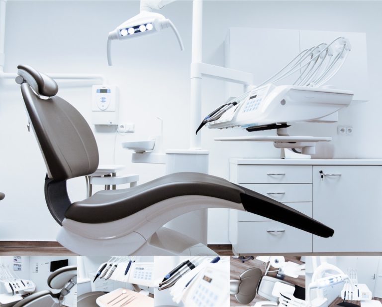 Modern dental office with an empty dental chair, overhead light, and various dental instruments and equipment arranged around the room.