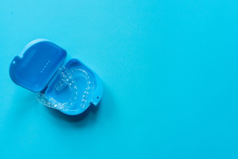 A set of Invisalign clear aligners in a blue protective case on a blue background
