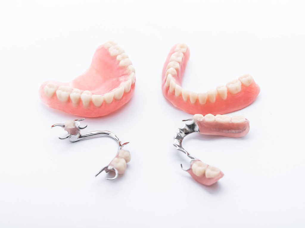 full dentures next to partial dentures on a white background
