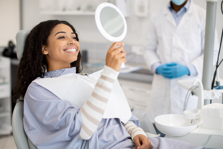 smiling woman looking at teeth in a mirror