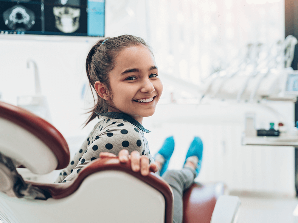 Young girl in a dental chair smiling.